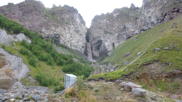 Glacial meltwater pours through an opening in the rocks above us....